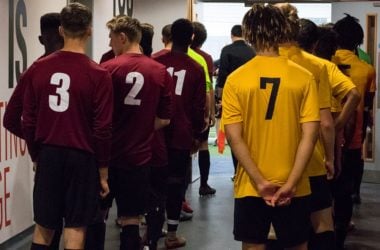Footballers lining up before a match in the tunnel with their squad numbers visible